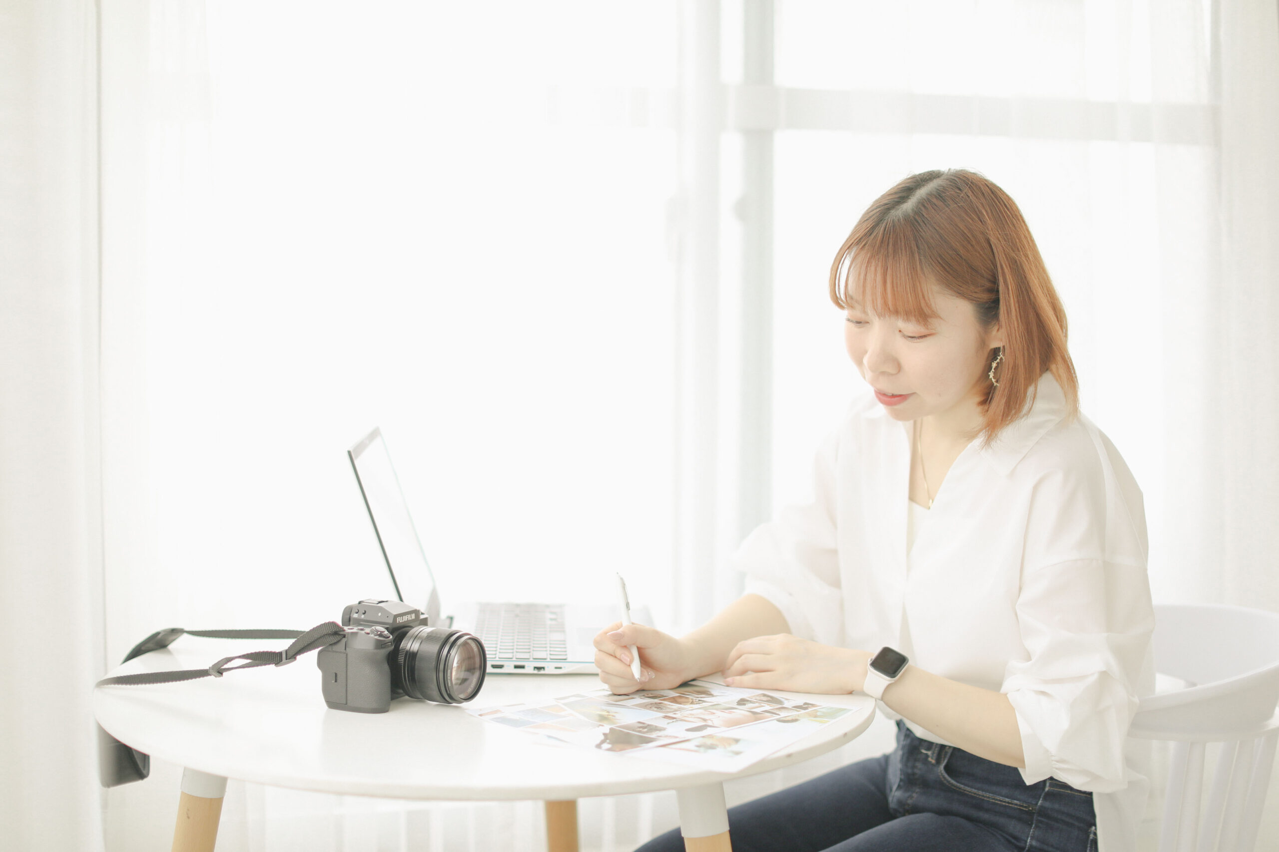 明るい窓辺でノートに書き込む今崎光美さん