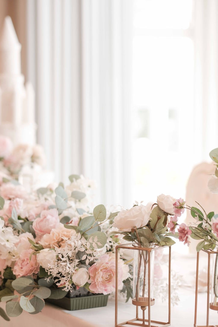 淡いピンクの花とキャンドルが並ぶ結婚式場